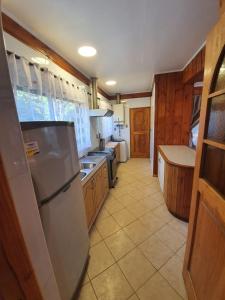 una cocina con nevera de acero inoxidable y armarios de madera en cabaña los robles en Licán Ray