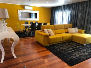 a living room with a yellow couch and a dining room at Luxury Chaves Village in Farroupo