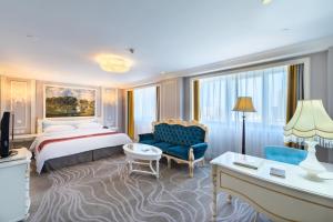 a hotel room with a king sized bed and a blue chair at Golden Ocean Hotel Tianjin in Tianjin