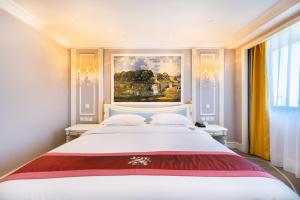 1 dormitorio con 1 cama blanca grande y una pintura en la pared en Golden Ocean Hotel Tianjin en Tianjin