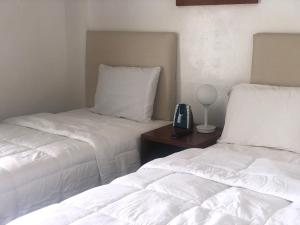 Un dormitorio con 2 camas y un teléfono en una mesa. en Coral Garden Hotel en Rota