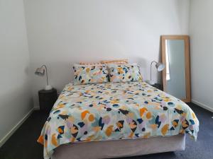 a bedroom with a bed with a colorful comforter at Wayamba in Warrnambool