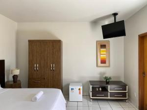 1 dormitorio con 1 cama y TV en la pared en B & A Suites Inn Hotel - Quarto Luxo Premium, en Anápolis