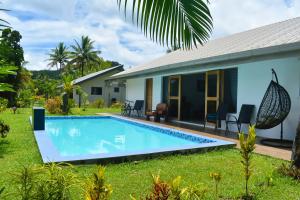 a villa with a swimming pool in front of a house at Island Villas Pacific Harbour in Pacific Harbour