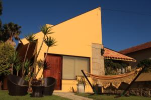 żółty dom z hamakiem przed nim w obiekcie Guesthouse Pool & Sea Espinho Oporto w mieście Espinho