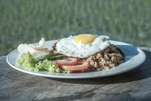 a plate of food with an egg on top of rice at Magatama Villa by Mahaputra in Gianyar