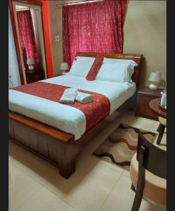 a bedroom with a large bed with red curtains at SMART INN GUEST HOUSE in Jwaneng
