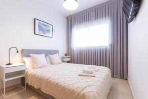 a bedroom with a large bed with a window and a white bedspread at AirTLV - Arlozorov Apartment's in Tel Aviv