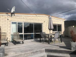 eine Terrasse mit einem Sonnenschirm, einem Tisch und Stühlen in der Unterkunft Solway House in Alexandra