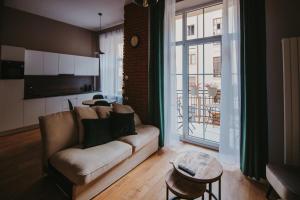 - un salon avec un canapé et une grande fenêtre dans l'établissement Apartament Green - Piotrkowska 37, à Łódź