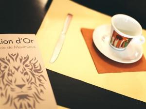 a cup of coffee on a plate on a table at Hôtel Restaurant Le Lion d'Or in Meximieux