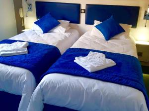 two beds with blue pillows and towels on them at Hôtel Les Alizés in Puget-Théniers