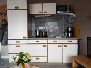 a kitchen with white cabinets and a microwave at Ferienwohnung Rhede in Rhede