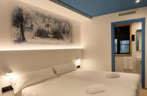 a bedroom with a white bed and a bathroom at Alameda Rooms Santiago in Santiago de Compostela