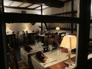 uma sala de jantar com mesas e cadeiras e um candeeiro em Auberge des Deux Rivières em Seix