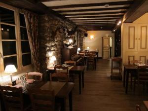 a restaurant with tables and chairs and a stone wall at Auberge des Deux Rivi&egrave;res in Seix