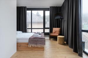 a bedroom with a bed and a chair and a window at Baza Smart Hotel in Bukovel