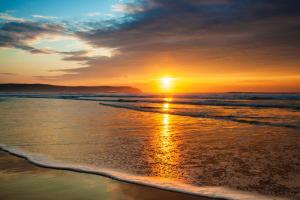a sunset on a beach with the ocean at The Woolacombe Bay Hotel in Woolacombe