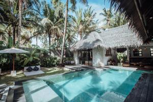 a swimming pool in front of a house with palm trees at Villa Tulua Siargao in General Luna