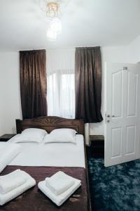 1 dormitorio con 2 camas con sábanas blancas y ventana en Casa Daiana, en Ocna Şugatag