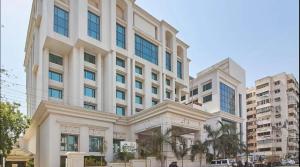 a large white building with palm trees in front of it at The Imperial Palace in Rajkot