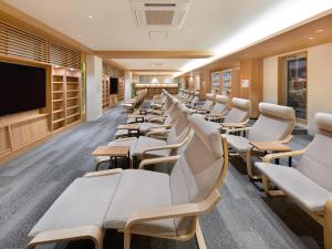 uma sala de espera com cadeiras brancas e uma televisão de ecrã plano em Smart Stay SHIZUKU Shinagawa-Oimachi em Tóquio