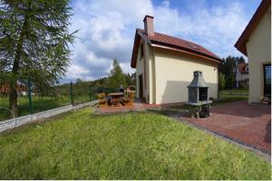 a house with a backyard with a grill in the yard at Komfortowe domki nad jeziorem - Zielony domek 1 in Kruklanki