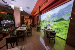 un restaurant avec des tables et des chaises et une grande fenêtre dans l'établissement Hotel Rivulus, à Baia Mare