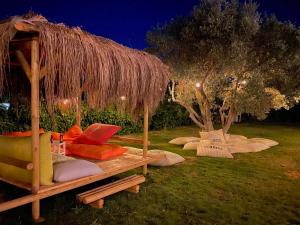 a bed with a straw umbrella and a tree at Alaçatı Barbarossa Hotel in Cesme