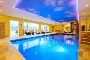 a large swimming pool in a house with a blue ceiling at Wellnesshotel Tanne in Baiersbronn