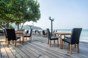 a row of tables and chairs on a wooden deck next to the ocean at Ao Prao Resort in Ko Samed