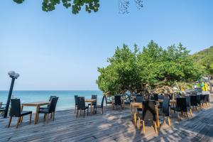 a row of tables and chairs on a deck next to the ocean at Ao Prao Resort in Ko Samed
