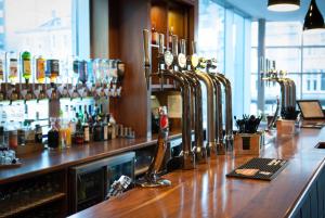 a bar with a counter with a lot of alcohol bottles at Leonardo Hotel Aberdeen in Aberdeen
