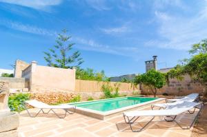 a swimming pool with two lounge chairs next to a house at Can Romaguera in Algaida