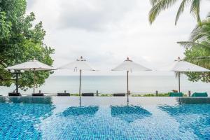 a swimming pool with umbrellas and the ocean at Ao Prao Resort in Ko Samed