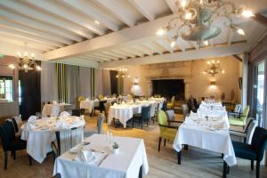 une salle à manger avec des tables et des chaises blanches dans l'établissement LOGIS Hôtel & Restaurant - LENSOTEL, à Lens