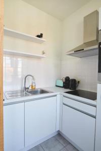 a kitchen with white cabinets and a sink at Apartments Villa Manalou in Wenduine