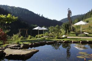 a pond with two white umbrellas in a field at Tanne Tonbach - Wellness & Wohlfühl Hotel in Baiersbronn +121 photos
