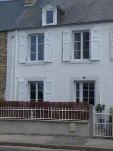 une maison blanche avec des fenêtres blanches à volets et une clôture dans l'établissement Gîte la presqu'ile, à Portbail