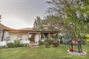 a house with a table and chairs in the yard at Klein Nektar Cottage in Montagu