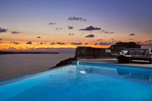 einen Pool mit Blick auf das Meer bei Sonnenuntergang in der Unterkunft Charisma Suites in Oia