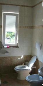 La salle de bains est pourvue de toilettes blanches et d'une fenêtre. dans l'établissement Apartman Dana, à Premantura