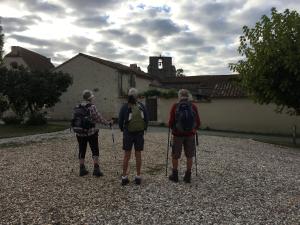 three people with backpacks standing in front of a building at La Ferme Buissonnière in Bardou