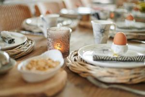 einem Holztisch mit Platten und Eiern darüber in der Unterkunft Gastenverblijf Huize Pervijze in Pervijze