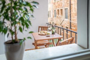 un tavolo con un cesto di cibo e bicchieri di vino sul balcone di Ca del Mar Venice Luxury Apartments a Venezia