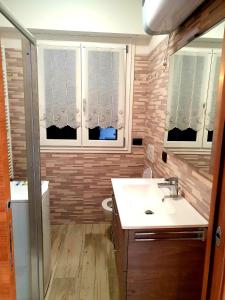 uma casa de banho com um lavatório, um WC e janelas em Casa Palabione em Aprica