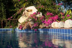 a swimming pool with pink flowers and a rock at Tafelberg detached bungalow with swimming pool in Chiang Rai