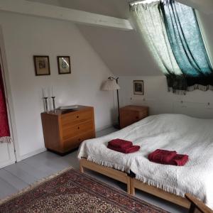 SvebølleMikrogaarden shared kitchen&bathroom的一间卧室配有一张带两个红色毛巾的床