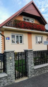 a house with a black fence and red flowers at Németh Vendégház in Bük