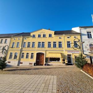 ein großes gelbes Gebäude in einer Kopfsteinpflasterstraße in der Unterkunft Gästezimmer Treuen - Bed & Breakfast in Treuen